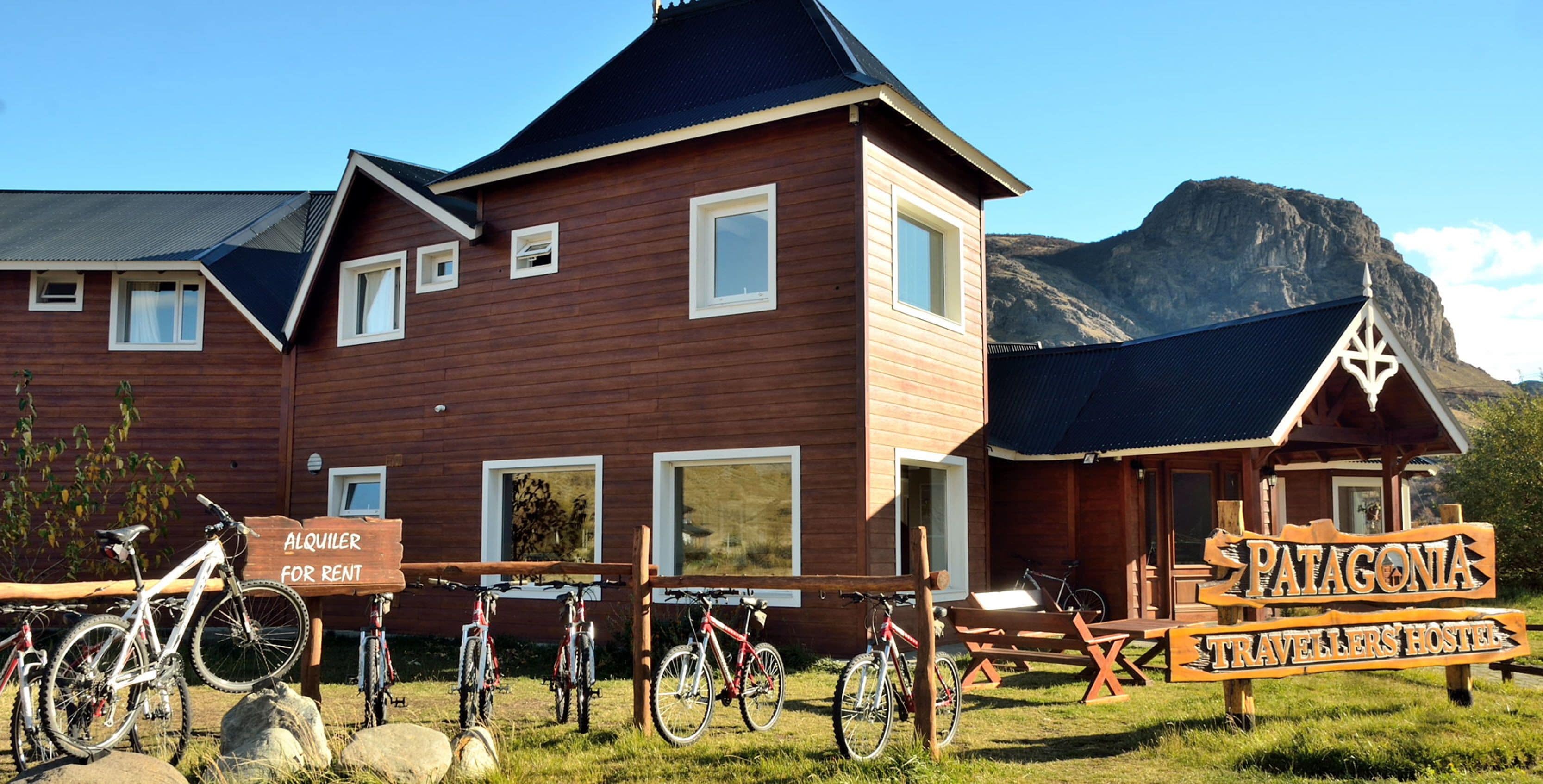 En byggnad av trä med en skylt där det står ”Patagonia Travellers’ Hostel”, och ett antal cyklar som står parkerade utanför.