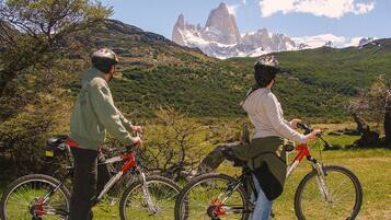 Two people on bicycles with a mountainous landscape in the background.