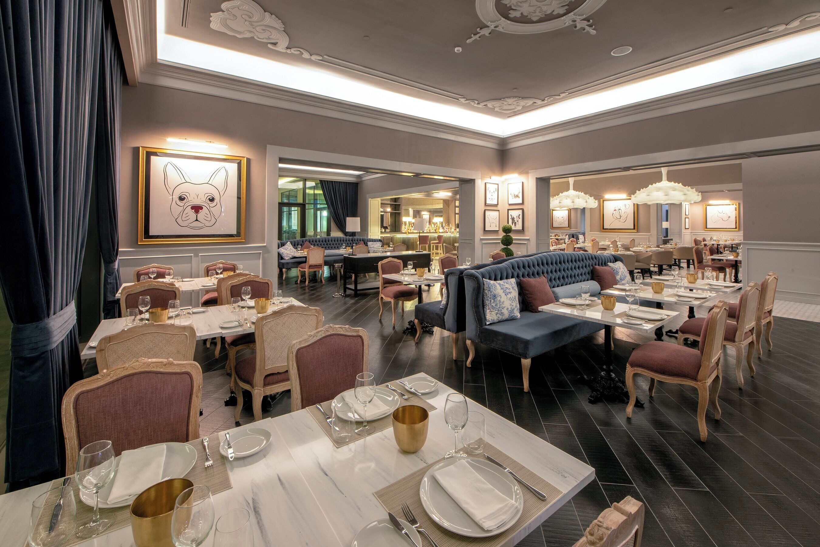 Un restaurante con varias zonas de comedor, que incluyen un bar y un área de estar con sofá y sillas.