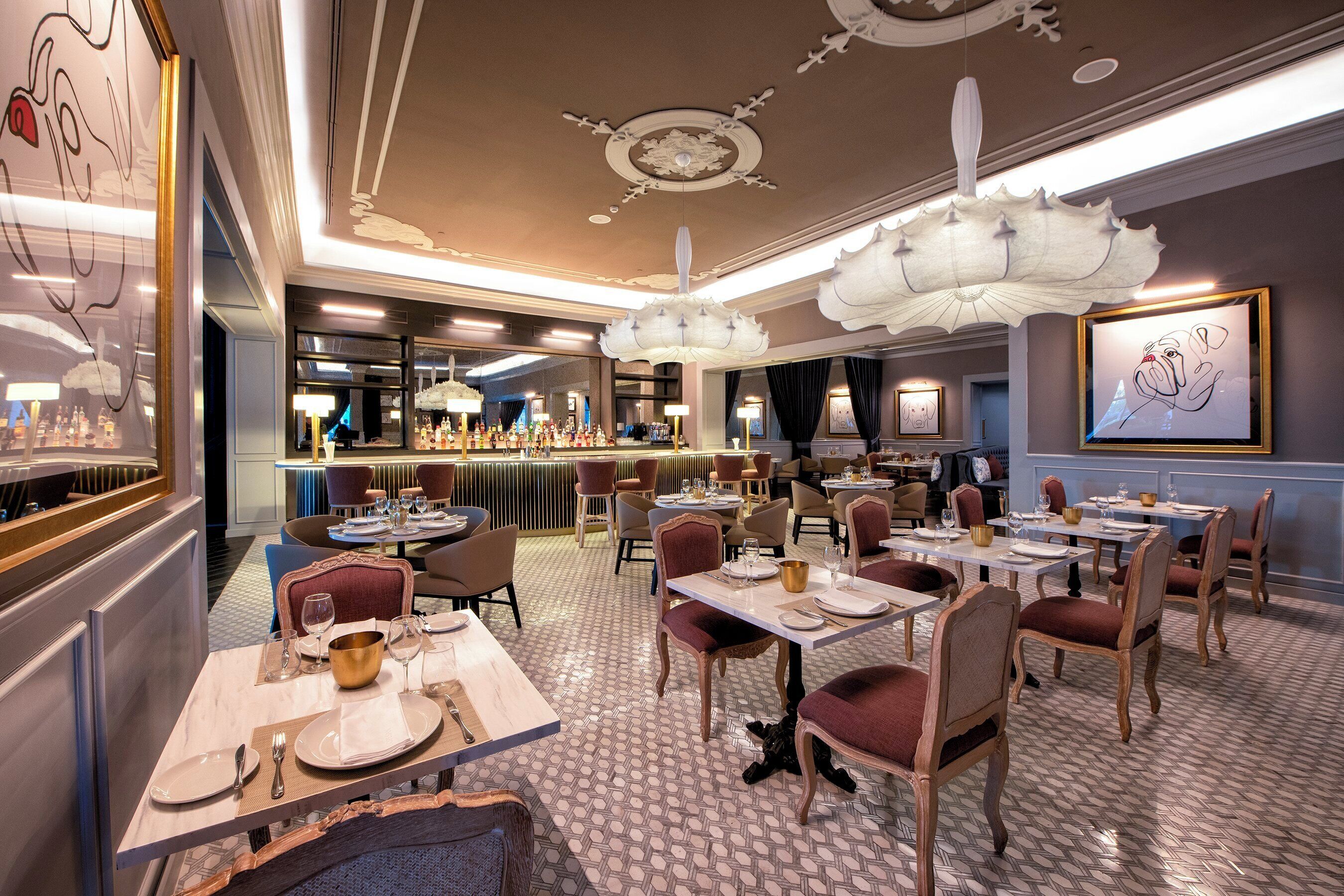 L'intérieur d'un restaurant, avec plusieurs tables, des chaises et un coin bar.