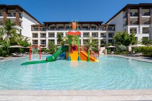 Ein Schwimmbecken mit bunten Wasserrutsche und einer mehrstufigen Spielanlage.