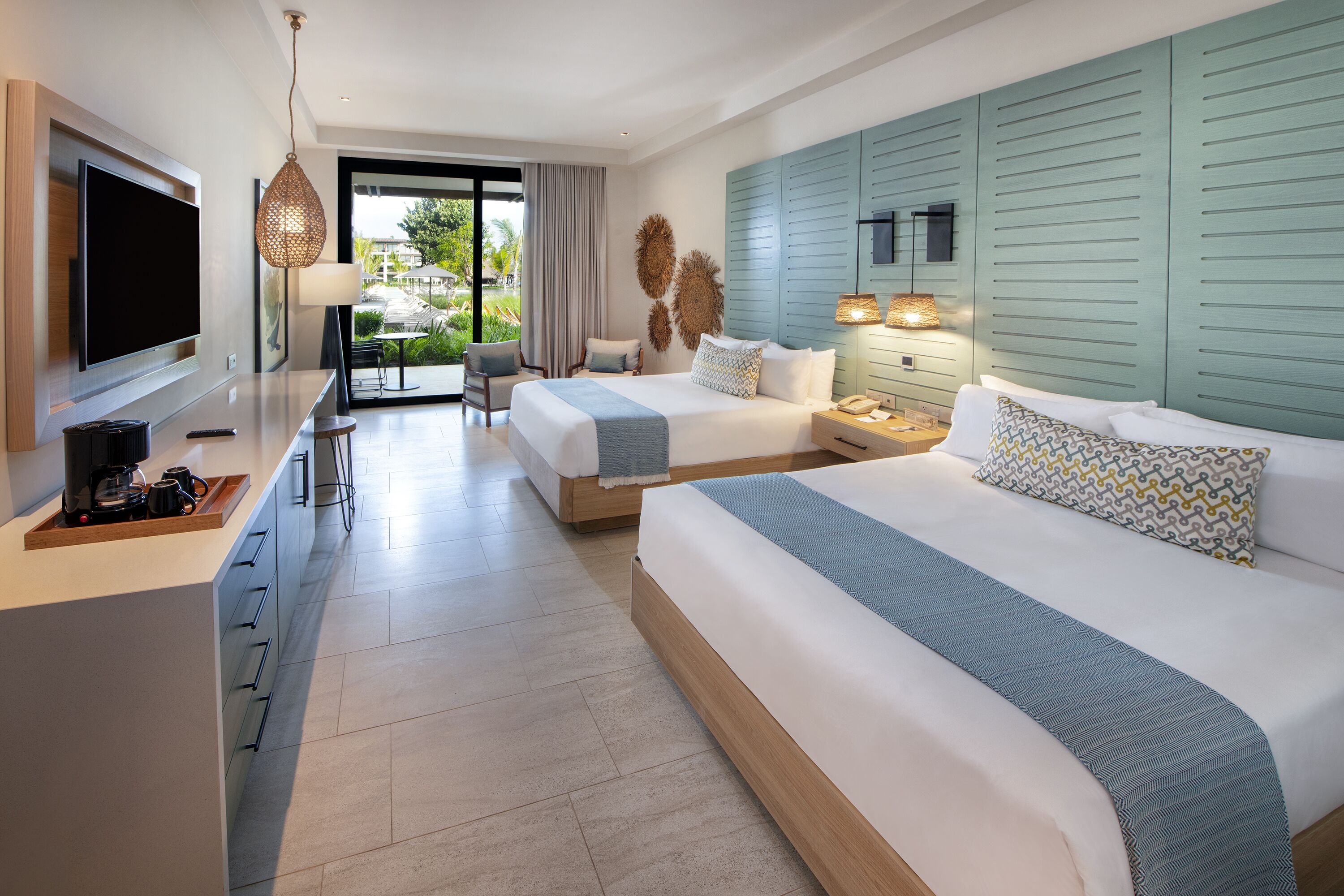 Camera d'albergo moderna con un letto grande, una scrivania con TV a schermo piatto e un'area pranzo con vista sull'esterno.