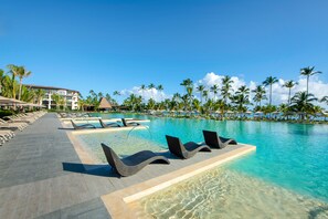 A resort pool area with lounge chairs and a clear view of the ocean.