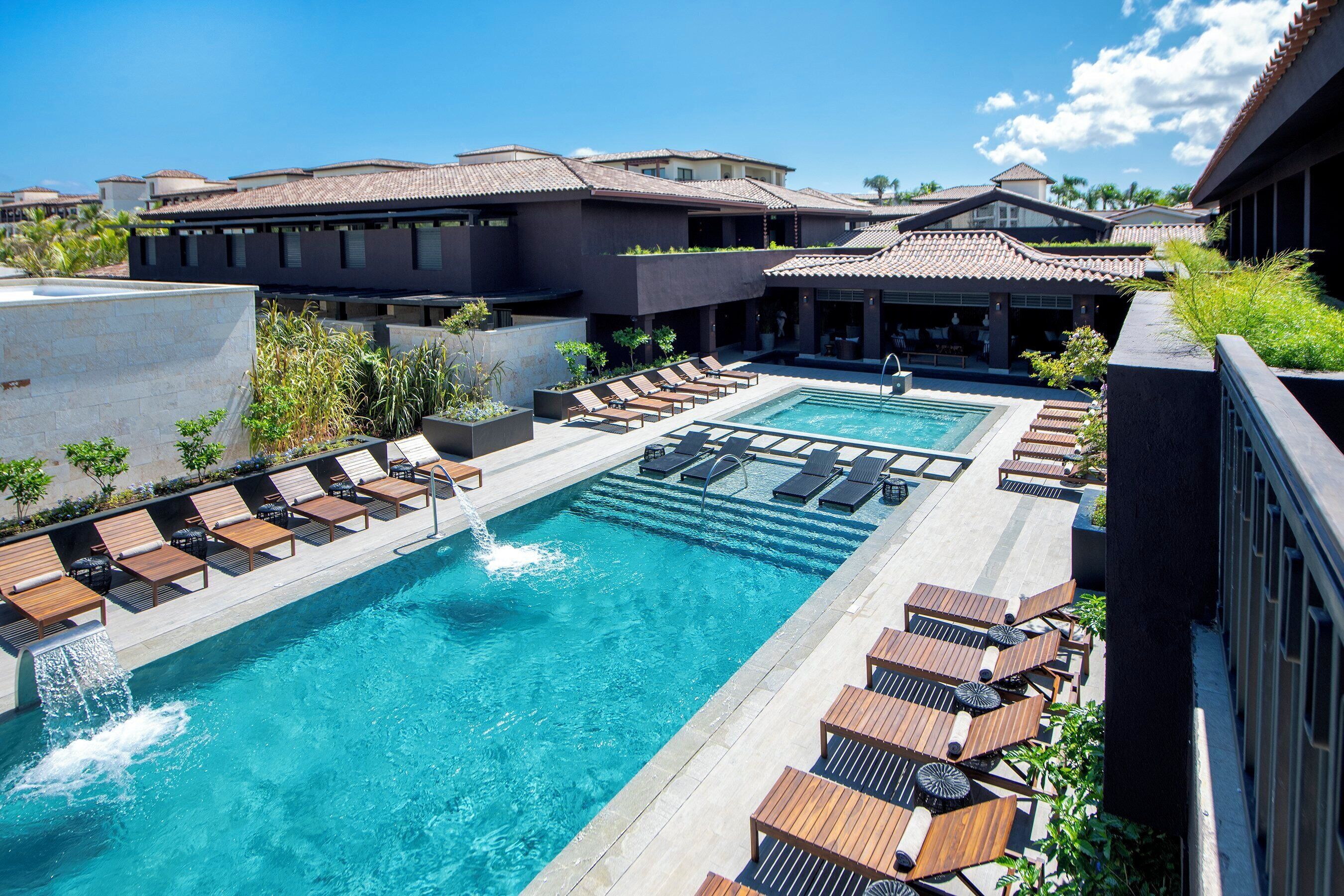 A rooftop pool area with multiple lounge chairs and a clear blue pool.