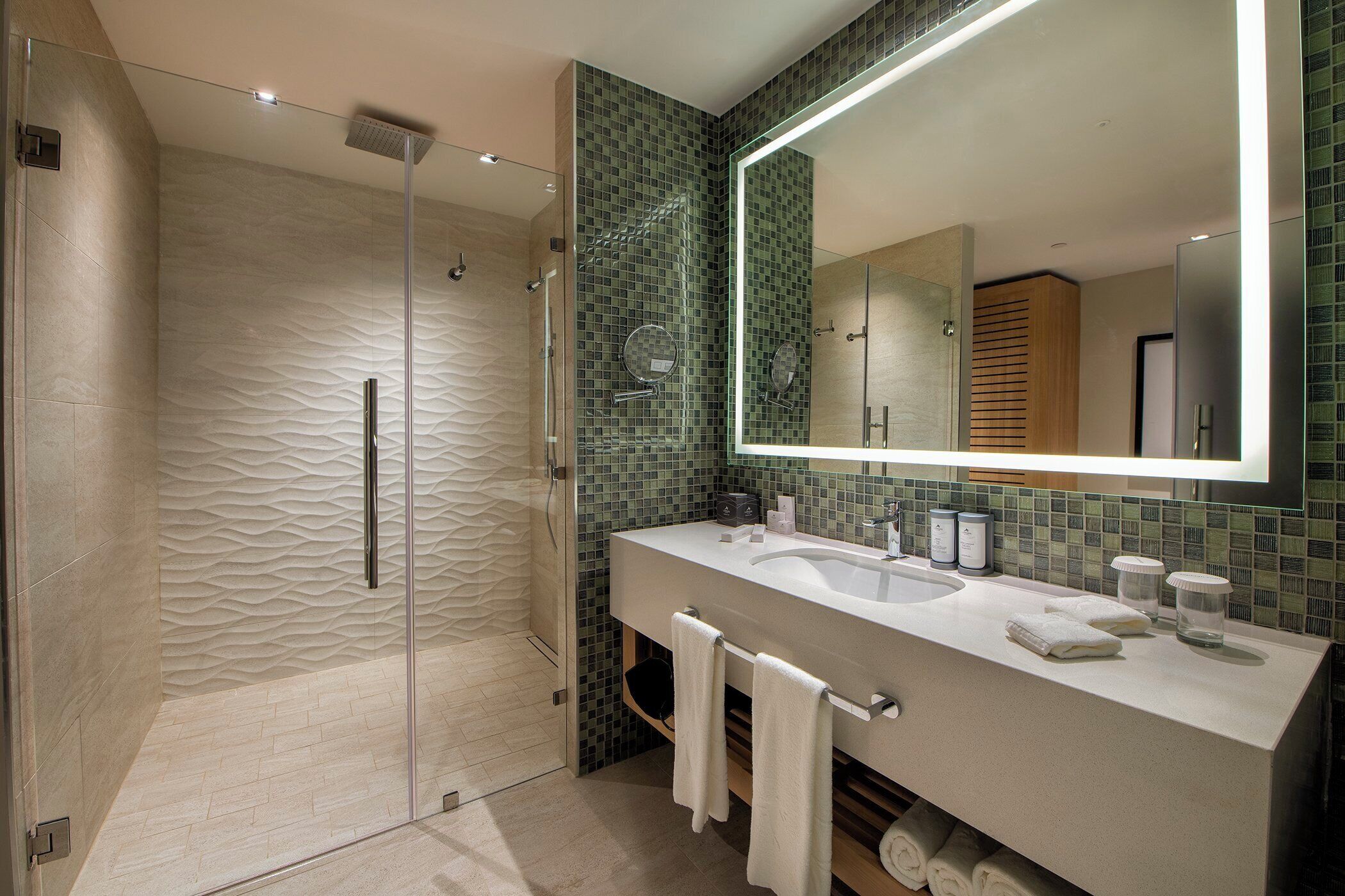 A modern bathroom with a glass-enclosed shower, a large mirror, and a vanity with two sinks.