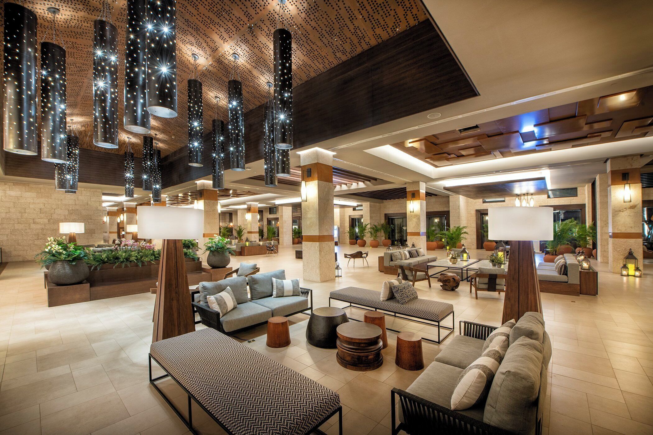 A spacious lobby with multiple seating areas, a high ceiling with hanging lights, and a mix of modern and traditional decor.