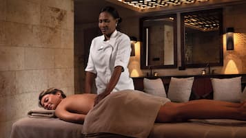 Een massageruimte met een massagetafel, handdoeken en een massagetherapeut.