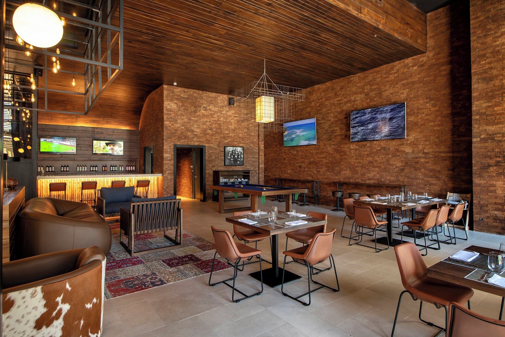 Een modern restaurant met bakstenen muren, een houten plafond en een bar met zitplaatsen.