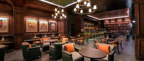A cozy, well-lit lounge area with wooden paneling, comfortable seating, and a bar area with shelves of bottles.