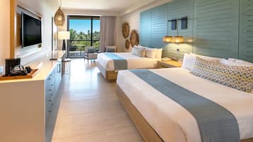 Habitación de hotel con dos camas, un escritorio, televisor y balcón con vistas.