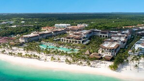 An aerial view of a resort with multiple buildings, a beach, and a pool.