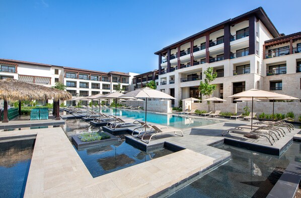 A hotel with a swimming pool, sun loungers, and umbrellas. - Adults Only Club at Lopesan Costa Bávaro - All Inclusive (Punta Cana)