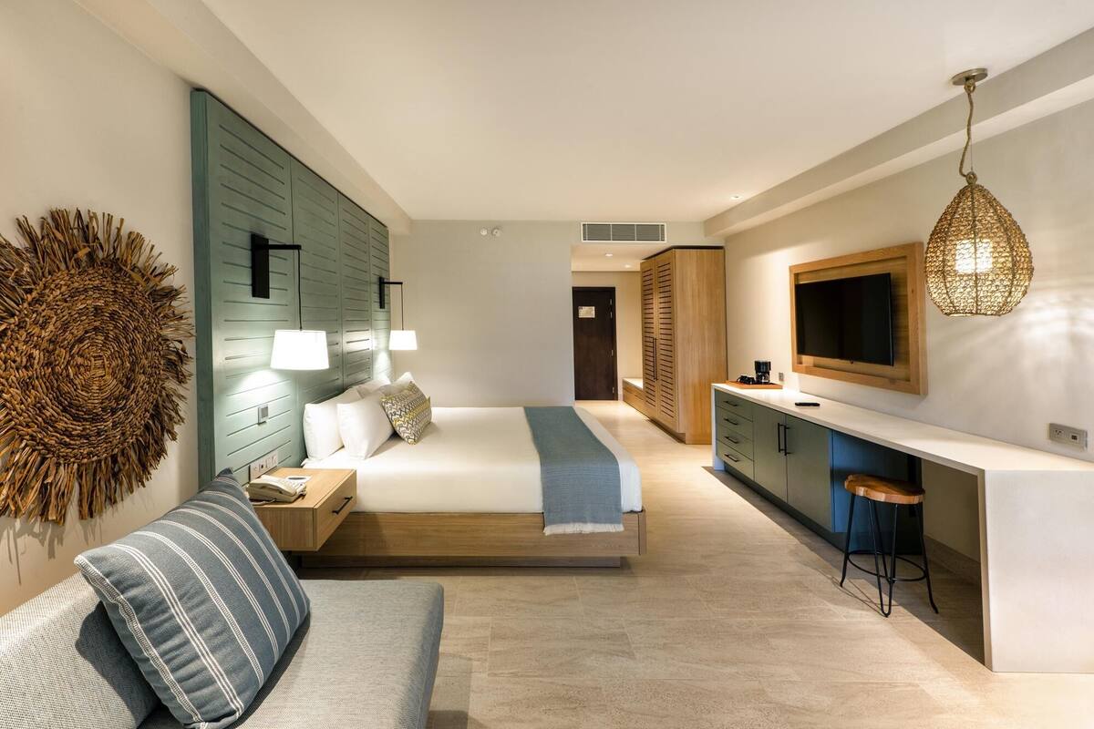 Ein modernes Hotelzimmer mit Bett, Sitzecke, einer Küchenzeile und einem Fernseher.