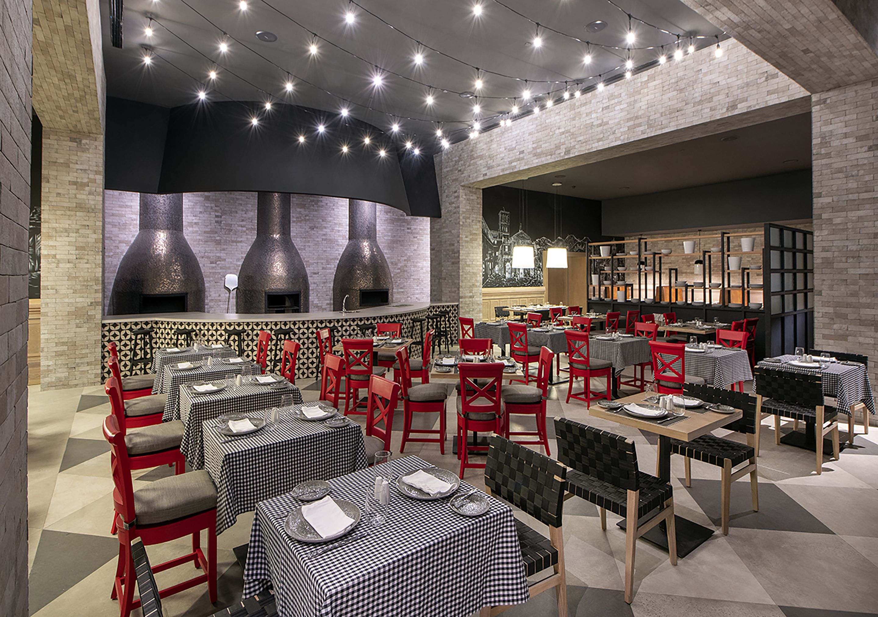 Un restaurant amb tovallons a quadradets, caires vermelles i una paret de maó.
