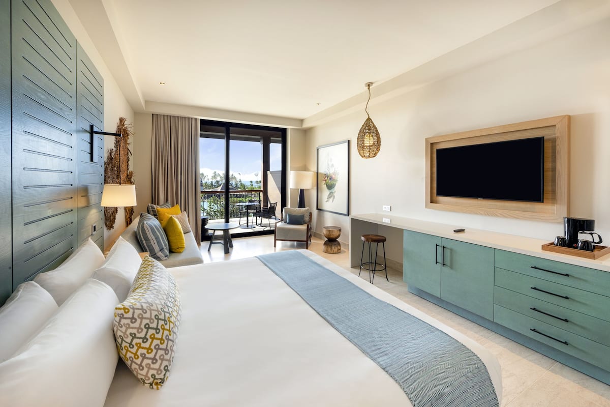 Ein modernes Hotelzimmer mit einem großen Bett, einem Balkon mit Aussicht, einer Küchenzeile und einem Flachbildfernseher.