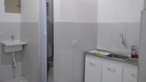 Un baño pequeño y limpio, con lavamanos, espejo y cabina de ducha.