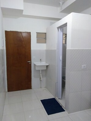 Uma casa de banho pequena com porta de madeira, lavatório branco e um porta-toalhas.