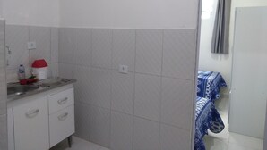 Un baño con azulejos blancos, un lavabo, un espejo y una zona de ducha.