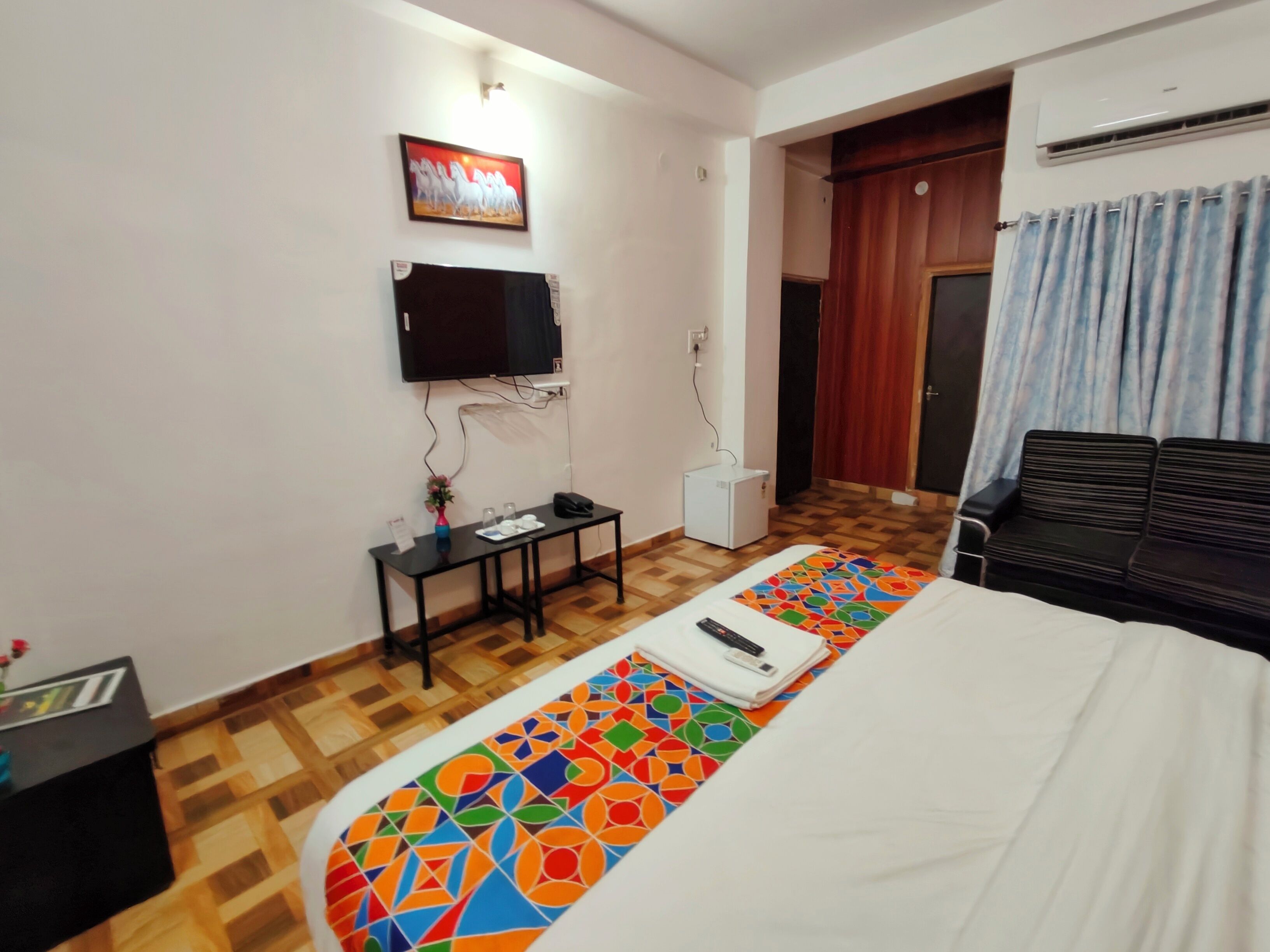 A hotel room with a bed, a desk, a television, and a wardrobe.