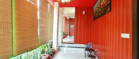 A corridor with red walls, a chandelier, and potted plants.