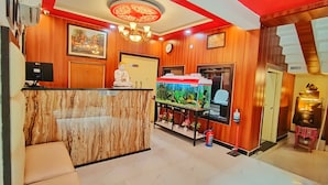 Een receptiezone met een marmeren balie, een groot aquarium, een Boeddhabeeld, een klok en een kroonluchter.