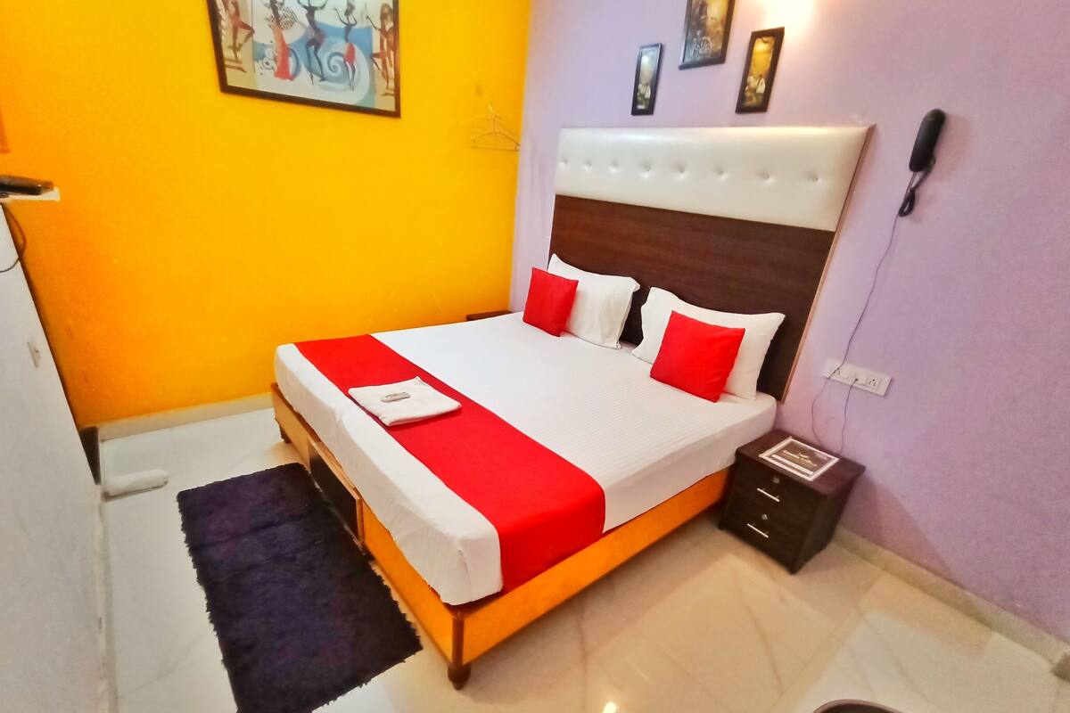 A neatly made bed with a red and white bedspread, a wooden headboard, and a small bedside table with a lamp.