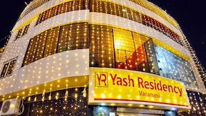 Een gebouw met een bord waarop 'Yash Residency Varanasi' staat, versierd met lichtslingers.