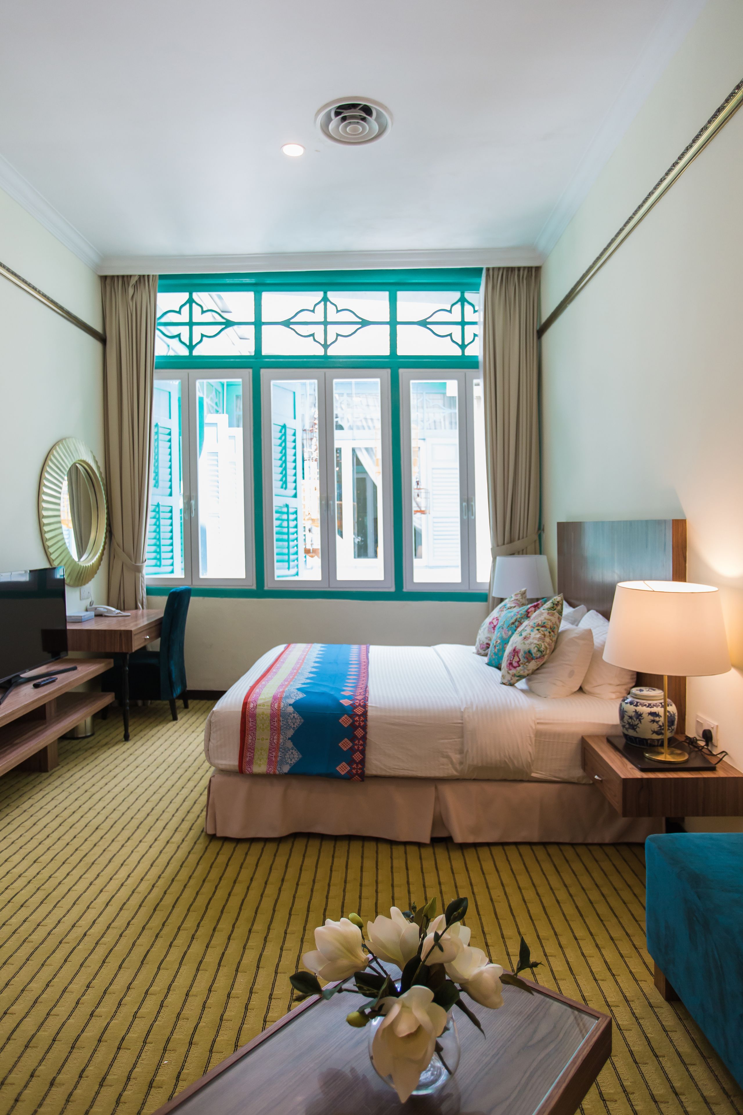 Habitación de hotel con cama, escritorio, silla y ventana con cortinas.
