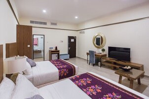 Una habitación de hotel con dos camas, un escritorio, un televisor y un espejo.