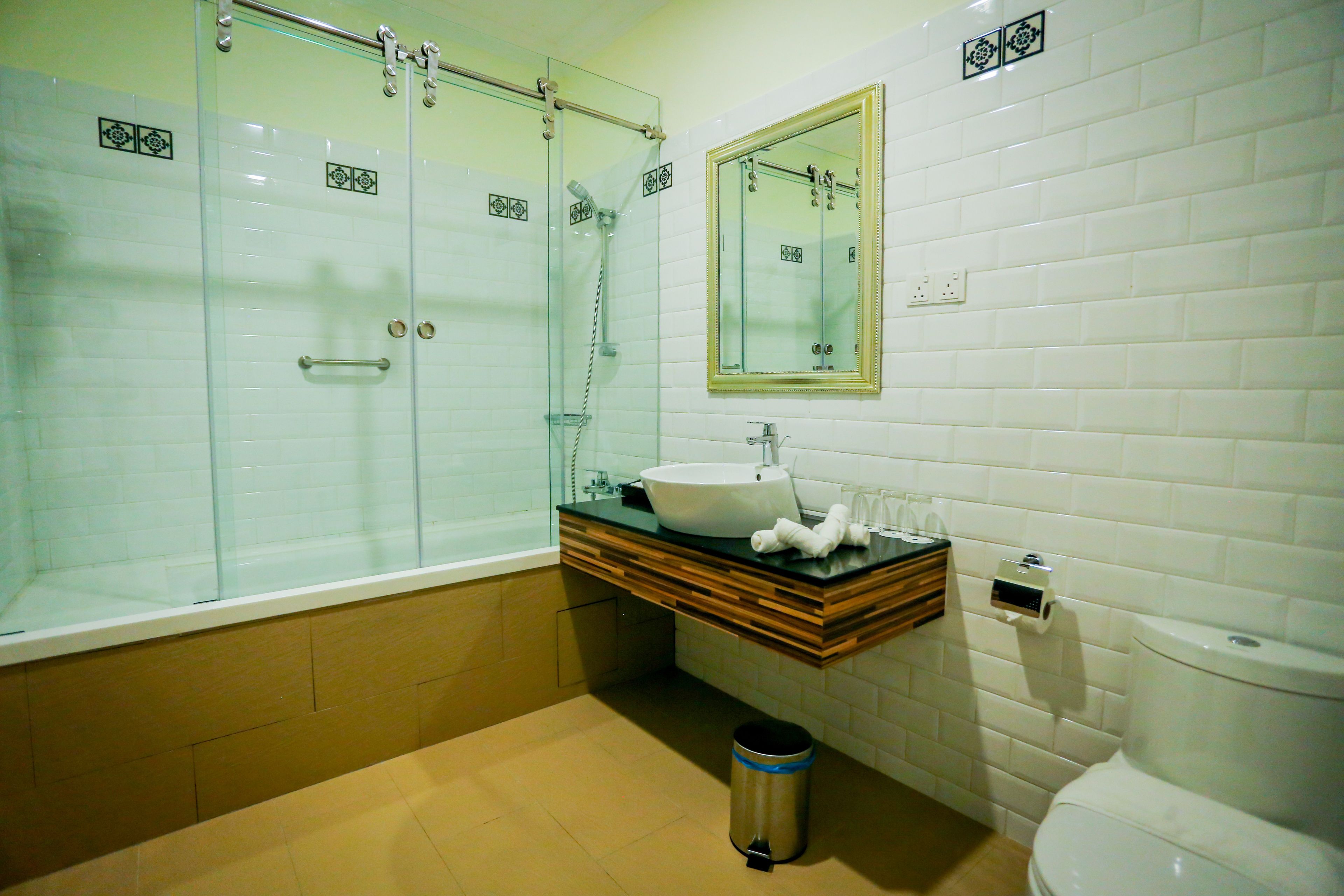 A bathroom with a glass-enclosed shower, a sink with a wooden vanity, and a toilet.