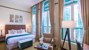 A hotel room with a bed, a chair, a table, and a window with curtains. - Aava Malacca Hotel (Malacca City)