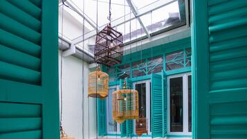 A room with teal shutters, a glass ceiling, and hanging birdcages.