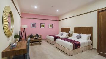 Habitación de hotel con dos camas, un escritorio, una silla, un espejo y una pared con tres cuadros enmarcados.