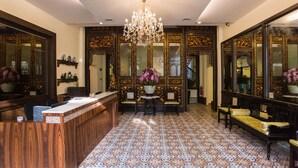 A lobby with a reception desk, seating area, ornate mirrors, and a chandelier. - Aava Malacca Hotel (Malacca City)