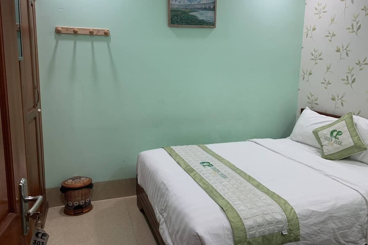 Ein Schlafzimmer mit einem Bett, einem kleinen Hocker, einer Holzablage und einem Bild an der Wand.