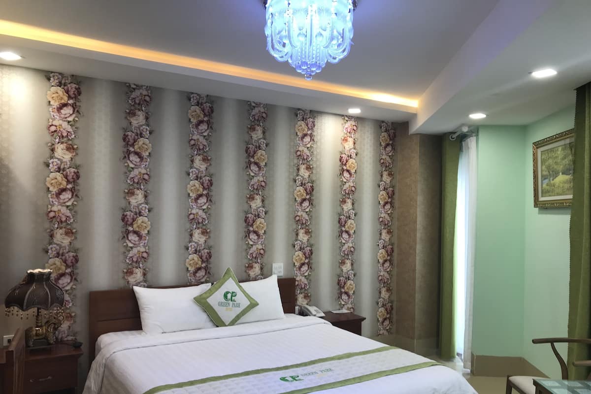 Ein Hotelzimmer mit einem großen Bett, floralem Wandpapier, einer Chandelier und einer grünen Akzentwand.