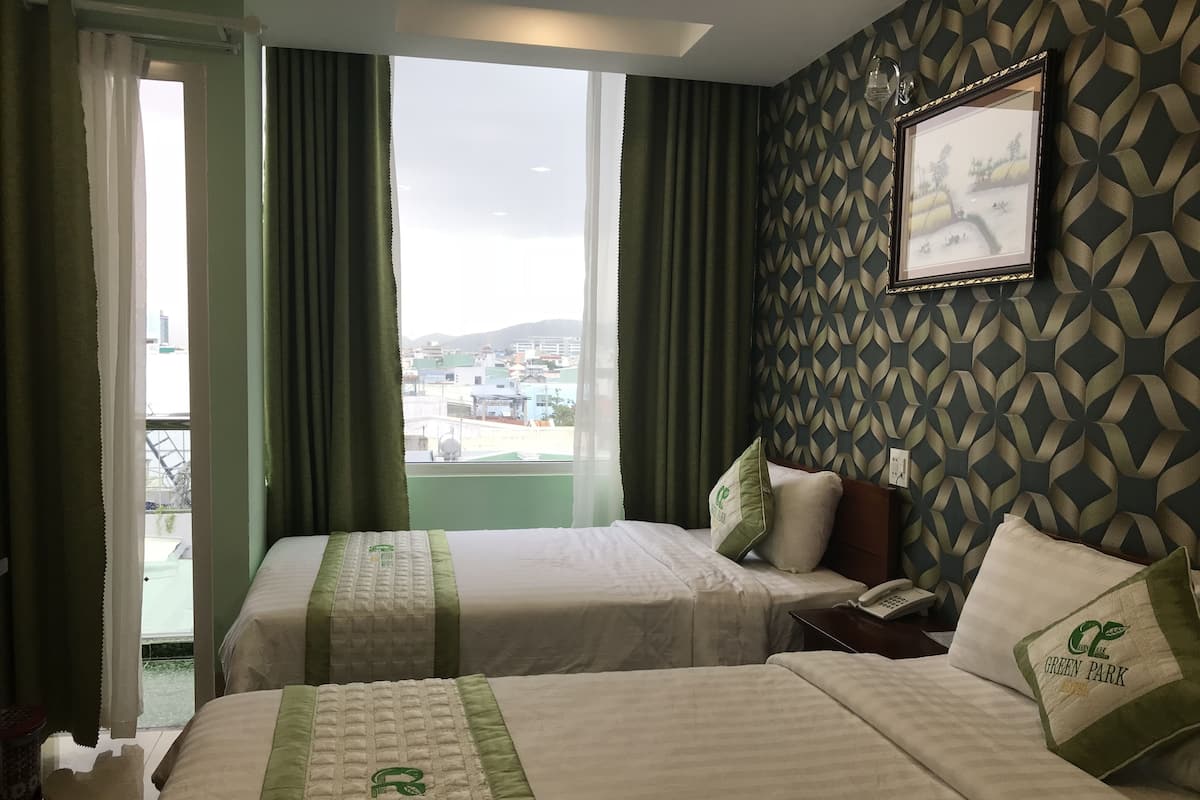 Ein Hotelzimmer mit zwei Betten, Blick auf die Stadt und einer Wand mit Muster.