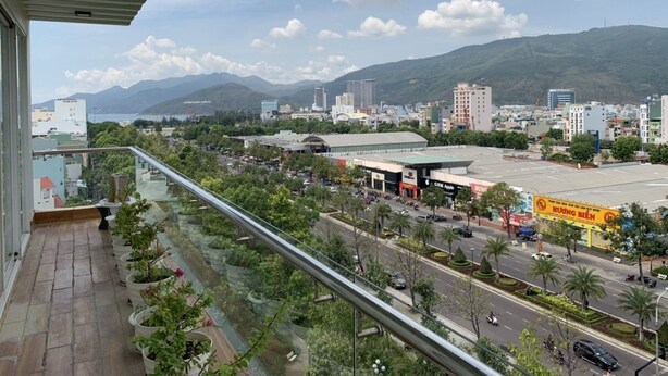 Un balcon offrant une vue sur le paysage urbain, avec des bâtiments, des routes et une montagne en arrière-plan.