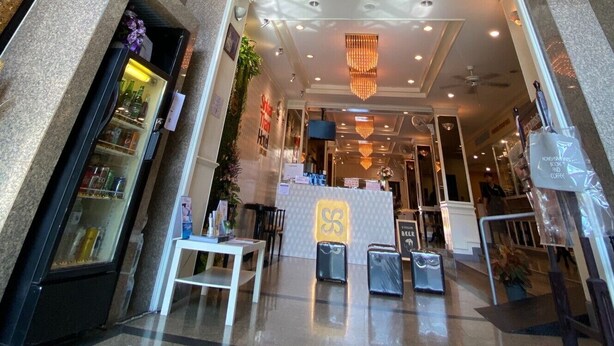 Vestíbulo de hotel con diseño moderno, que incluye un mostrador de recepción, zona de estar y vistas al piso superior a través de un techo de vidrio.