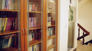 A wooden bookshelf filled with books, a wooden staircase, and a door leading to another room. - HomestyleHomestay (Jincheng)