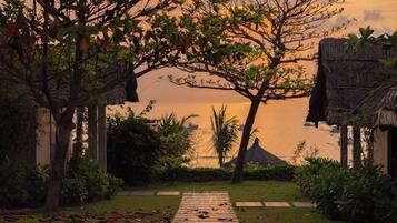 A pathway leading to a thatched-roof structure with a view of the water.