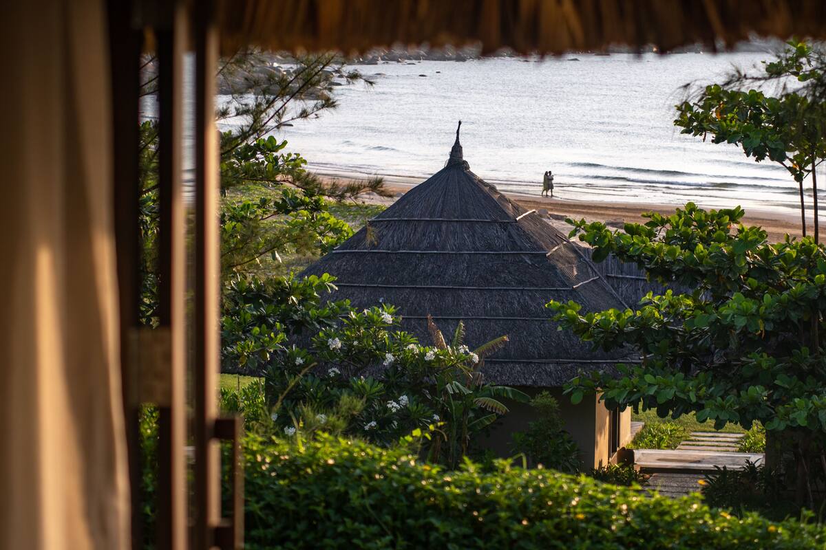 Une construction à toit de chaume offrant une vue sur la plage et l’océan.