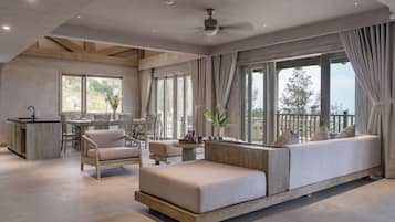 A spacious living area with a sofa, chairs, a dining table, and a kitchen area.