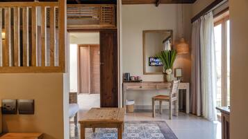 Una habitación con un escritorio de madera, una silla, una mesita, un espejo y un televisor.