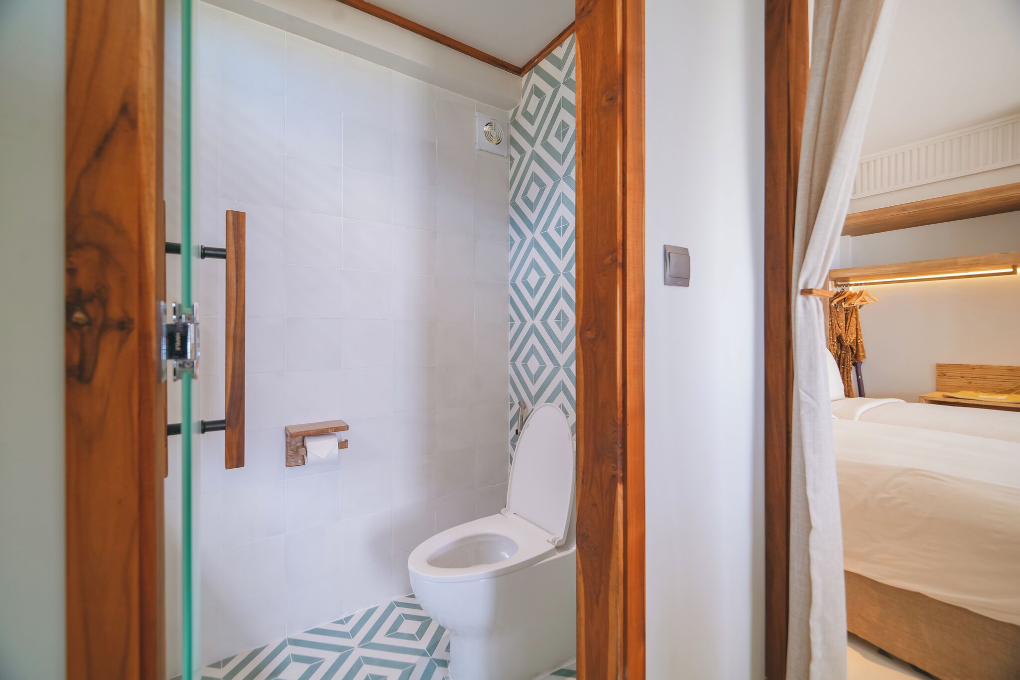 Un baño con ducha, inodoro y cama con cabecera de madera.