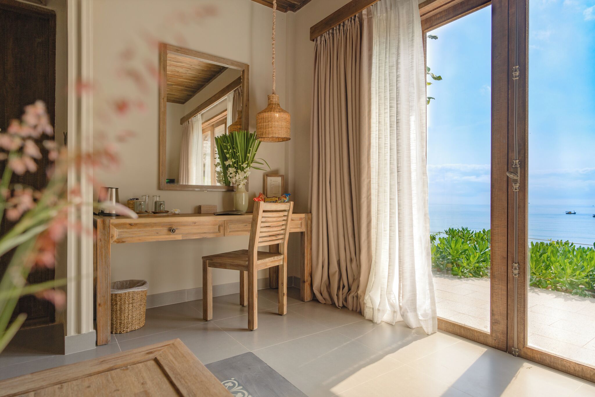 Una habitación con un escritorio de madera, una silla y un amplio ventanal con cortinas.