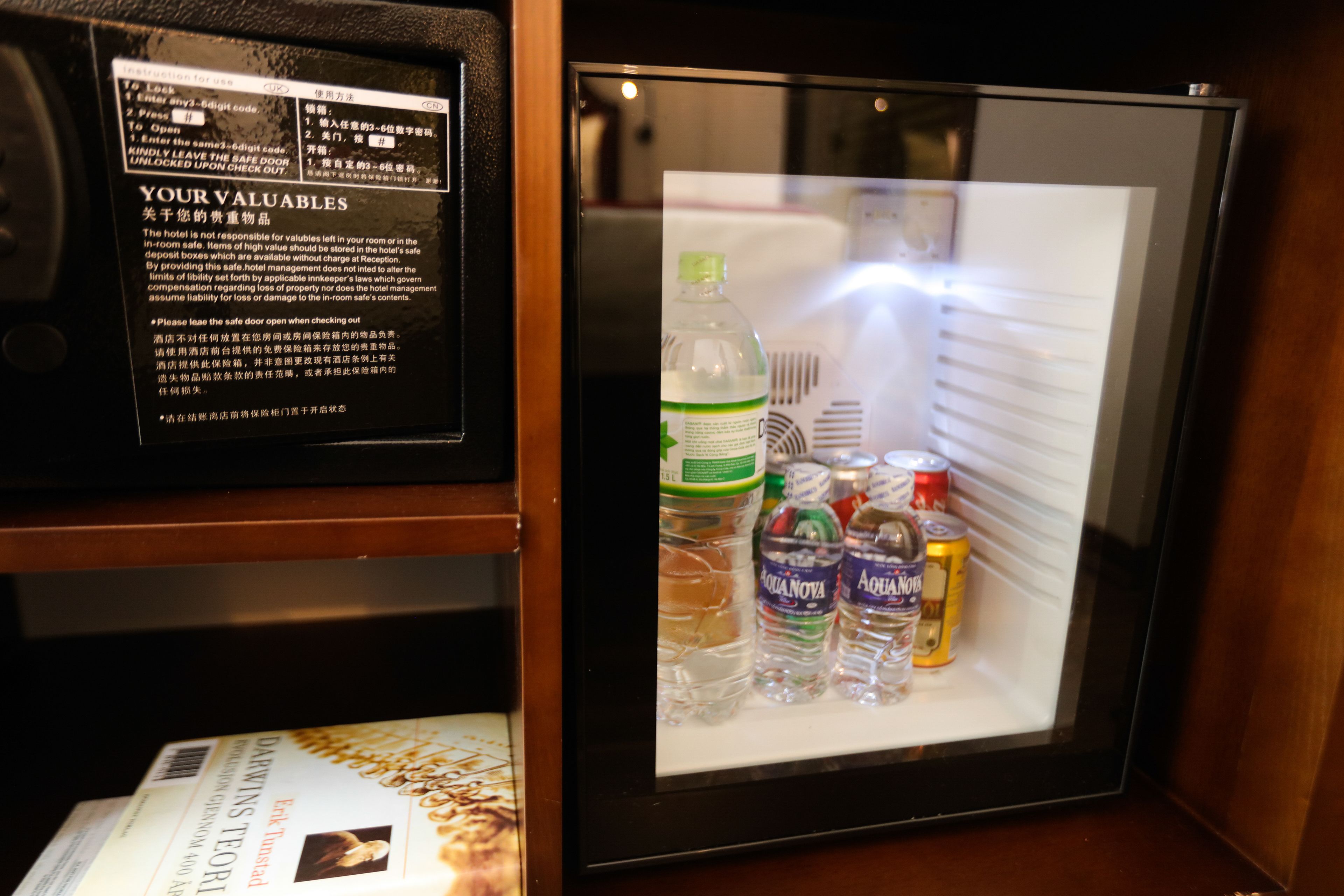 A refrigerator with a notice about valuables and a selection of bottled water and beverages.