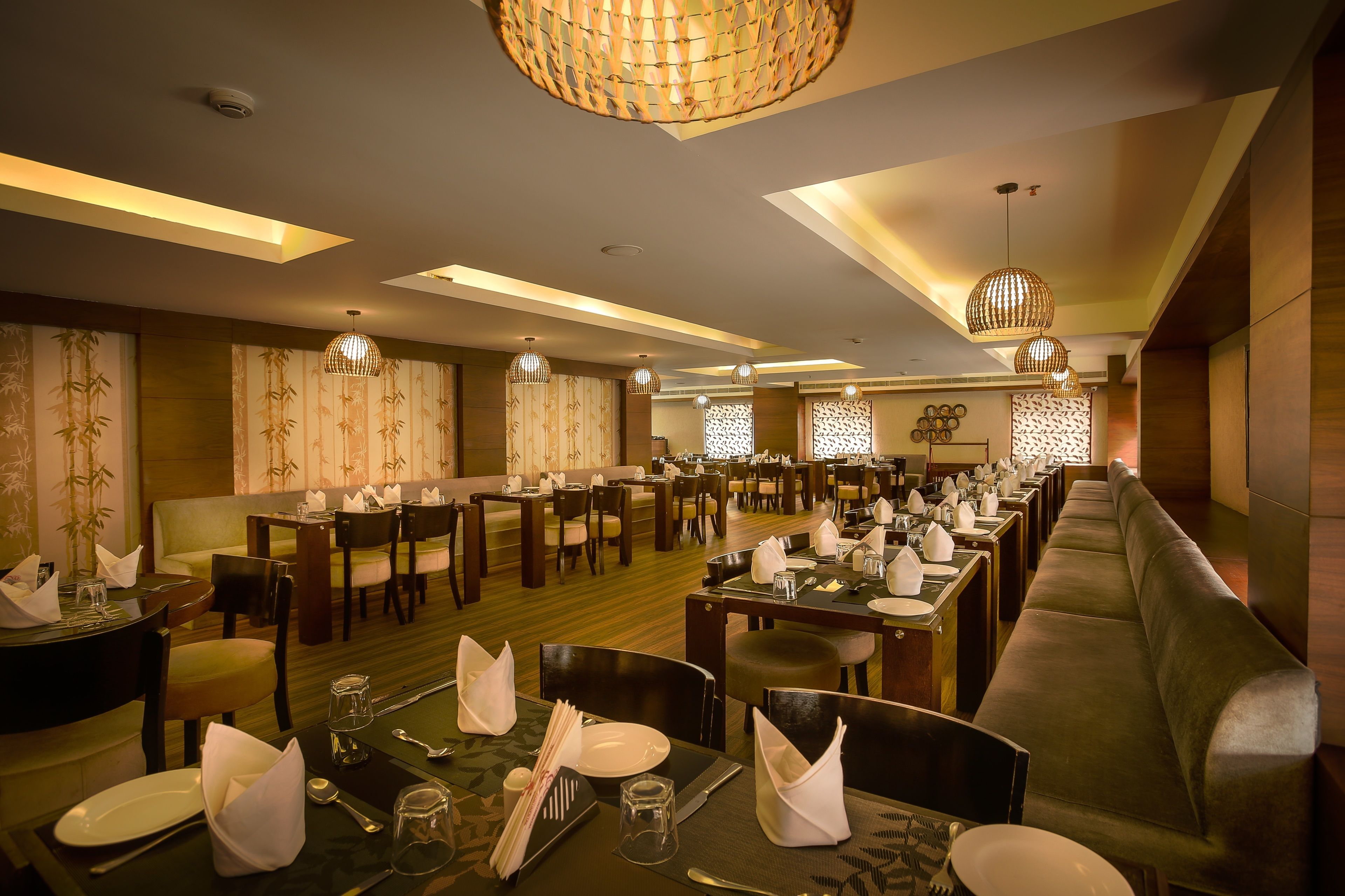 A restaurant with multiple dining tables set for guests, featuring a modern interior with patterned wallpaper and ambient lighting.