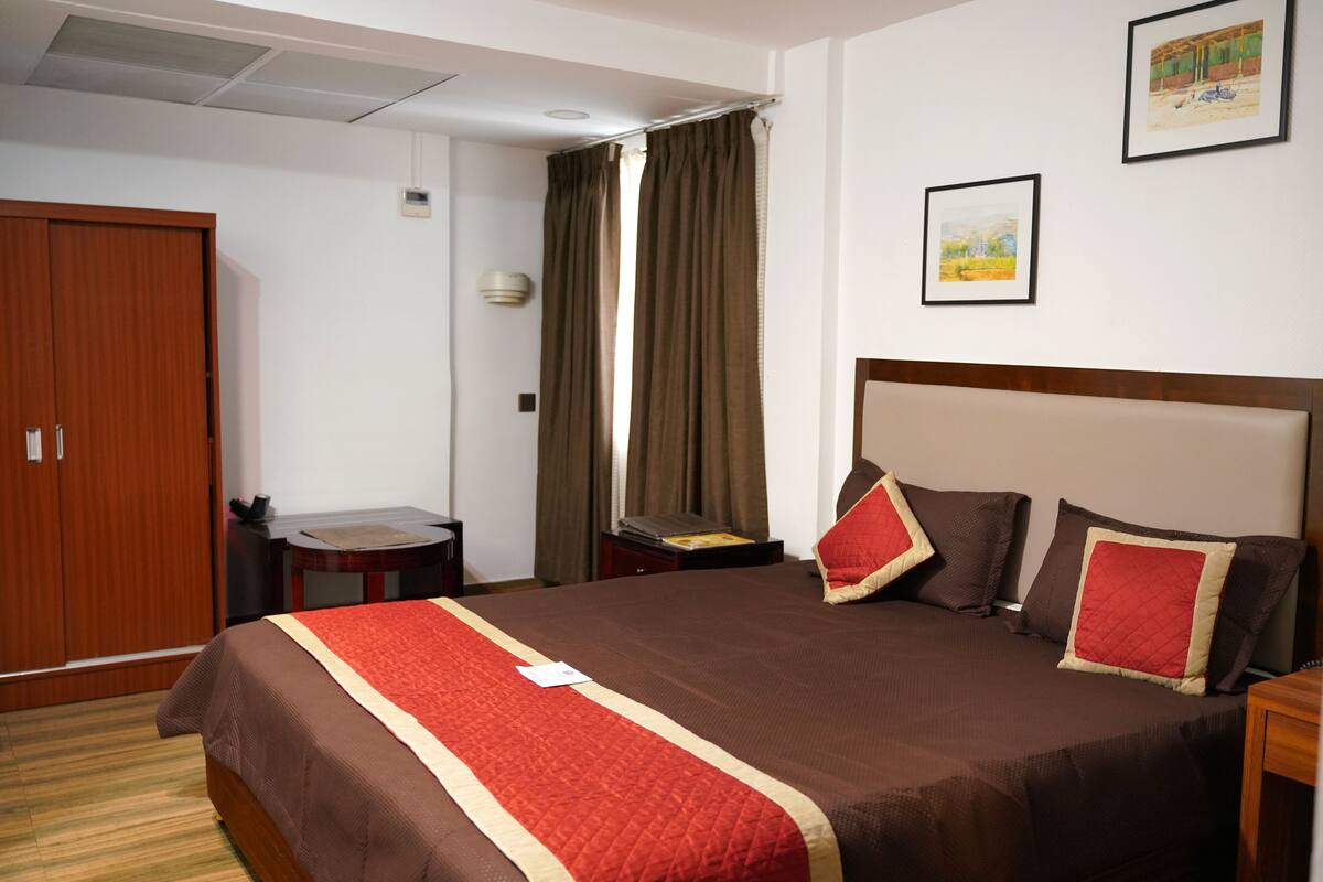 Een hotelkamer met een groot bed, een houten garderobe, een kleine tafel en een bureau.