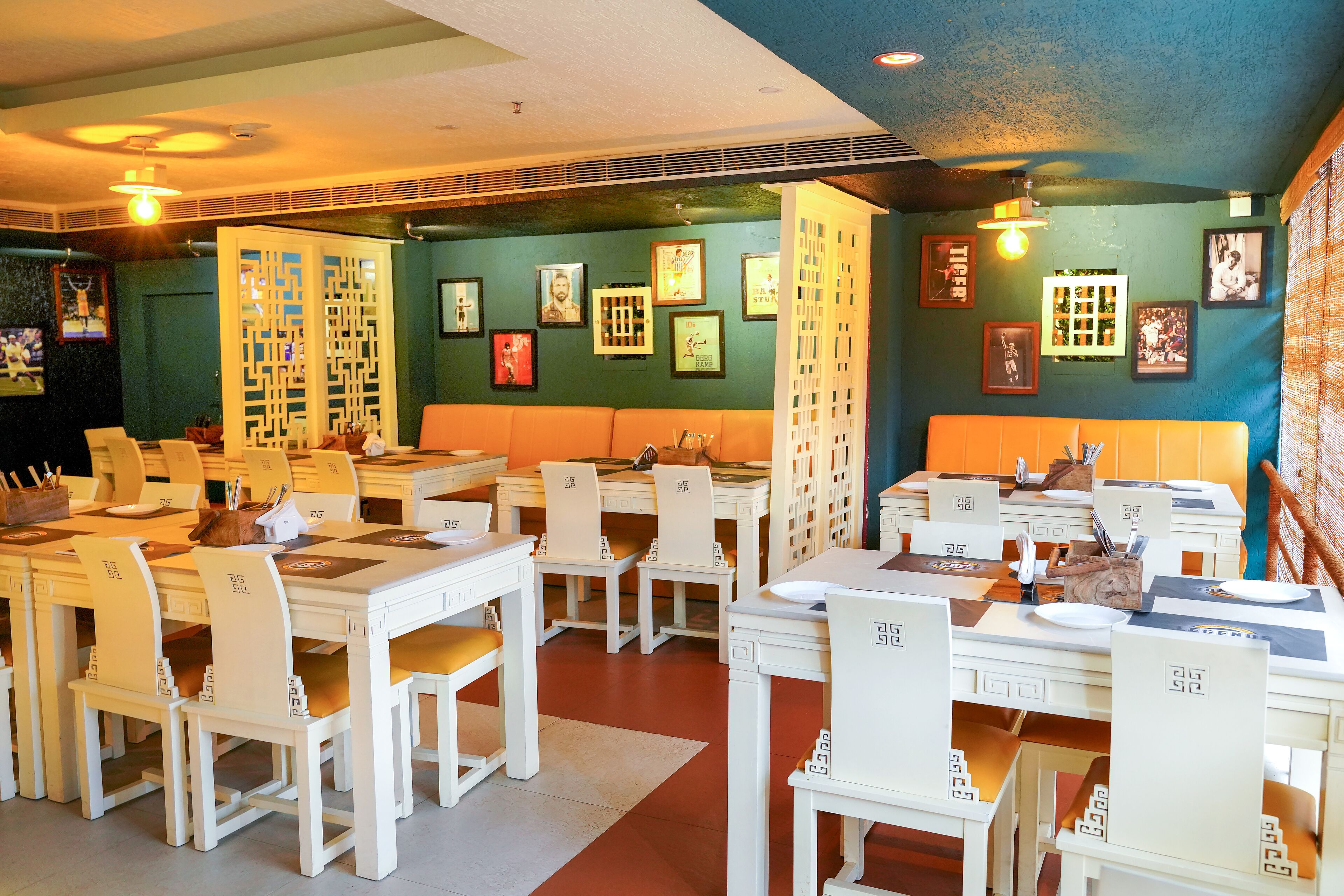 A restaurant with white furniture, green walls, and framed pictures on the walls.